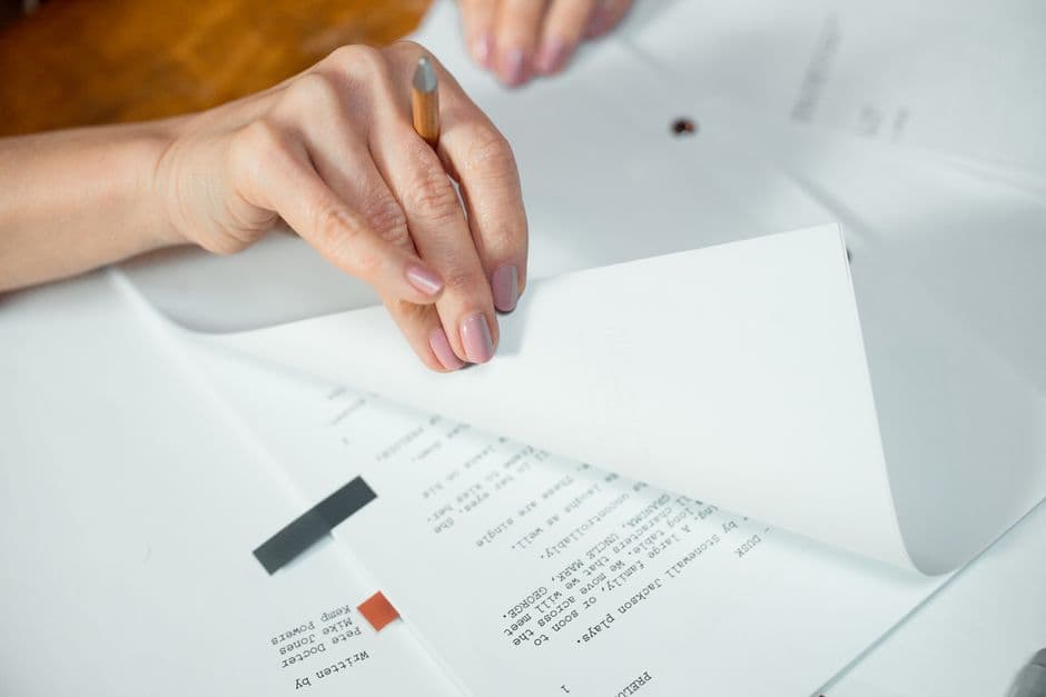 書類のページをめくりながら内容を確認している手元